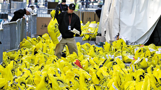 주인 잃은 마라톤 가방들… 미국 보스턴 마라톤 대회 관계자가 16일 마라톤 참가자들이 놓고 간 소지품 가방을 돌려주기 위해 번호를 확인하고 있다. 비닐 재질의 대회 가방에는 각 참가자들의 등록 번호가 붙어 있다.