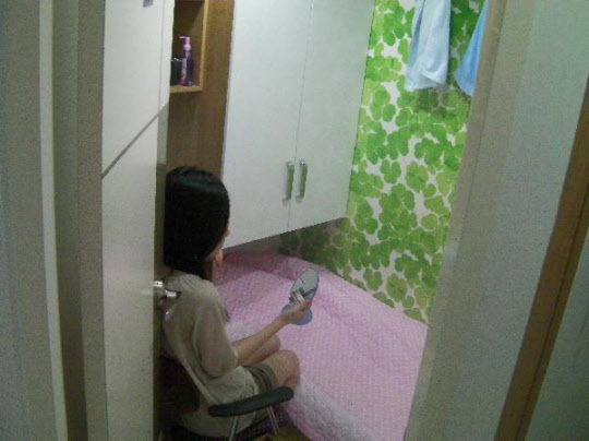 서울 영등포구에 있는 고시원에 살고 있는 한 여성이 앉아서 거울을 보고 있다. / 조선일보 DB