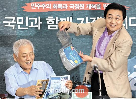 
	민주당 전병헌(오른쪽) 원내대표가 9일 서울시청 앞 천막당사에서 투명지갑에서 돈이 새는 퍼포먼스를 하고 있다. 왼쪽은 김한길 대표
