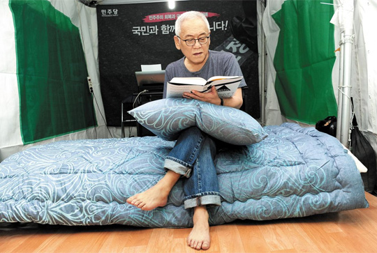 김한길 노숙투쟁 돌입… 집에 귀가하지 않는 노숙(露宿) 장외투쟁에 27일 들어간 민주당 김한길 대표가 천막당사 옆에 마련된 별도 천막 내 침대 위에 앉아 책을 읽고 있다. 김 대표는 노트북 컴퓨터와 책상, 야전침대가 갖춰진 이 천막에서 당분간 숙식을 할 예정이다