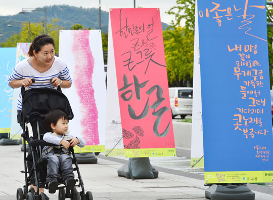 
	한글날을 앞두고 7일 오후 서울 세종로 광화문광장에서 열린‘한글 멋글씨전’에서 한 여성이 유모차에 아이를 태우고 다양한 글씨체로 쓰인 한글 전시물을 구경하고 있다.
