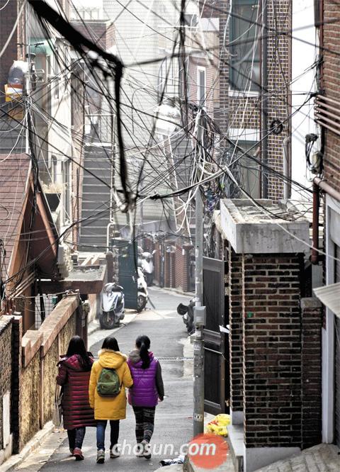 서울 용산구 이태원동 한남뉴타운 2구역에서 전깃줄이 거미줄처럼 얽힌 좁다란 골목길을 어린 학생들이 걸어가고 있다. 한남2구역은 서울시의 건축물 고도 제한에 따른 신축 아파트 수 감소와 일부 주민의 반대로 재개발 사업이 중단돼 있다