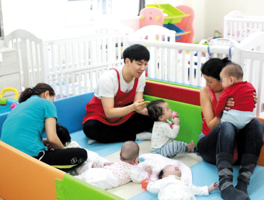 
	문상호 기자(가운데)가 보육사, 자원봉사자들과 함께 입양대기아동들에게 이유식을 먹이고 있다.
