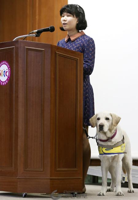 안내견 루시와 함께… 15일 서울 강북구 국립재활원에서 윤서향 서울 삼선중학교 교사가 안내견과 함께 단상에서‘꿈을 향한 행복한 도전’을 주제로 강의하고 있다.