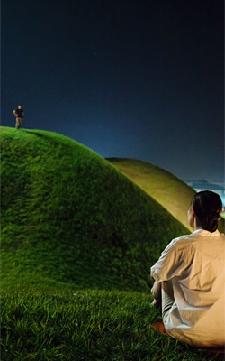 
	영화 ‘경주’의 한 장면. 공윤희가 능 위의 최현을 바라보고 있다. photo 언니네
