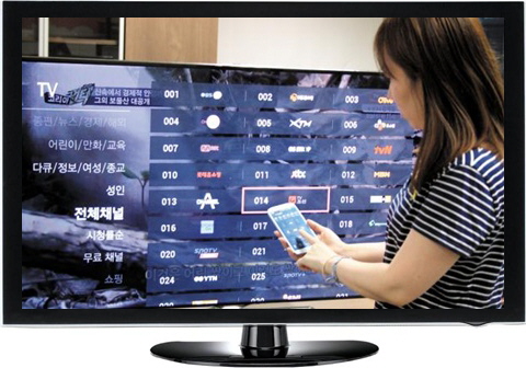 ‘티빙스틱’을 TV에 연결한 뒤 스마트폰으로 채널을 선택하고 있다.