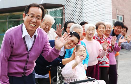 지난 19일 경기도 용인시의 작은손길 공동체 요양원에서 최만재(57·왼쪽 맨 끝) 원장과 이곳에 사는 노인들이 환하게 웃으며 손을 흔들고 있다.