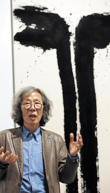 광목에 먹으로 그린 '폭포' 앞에 선 김호득.
