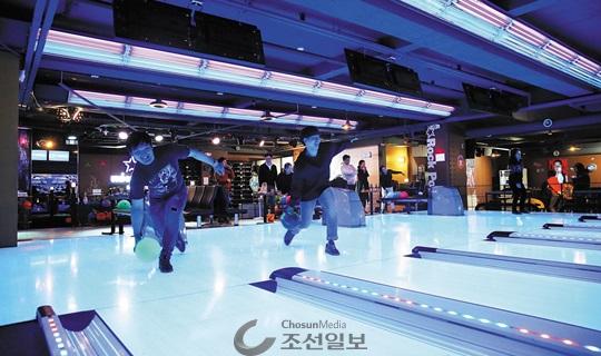 클럽을 연상시키는 조명이 비치는 야광 레인에서 야광공으로 볼링을 즐기는 볼링펍.