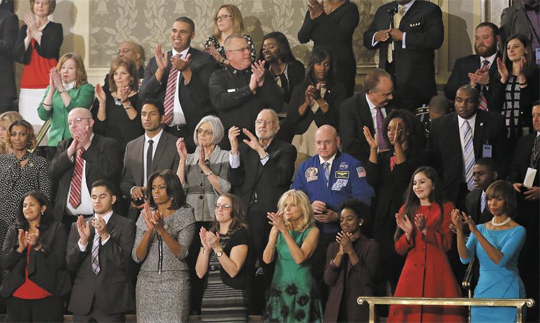 지난 20일 새해 국정연설 도중 버락 오바마 미국 대통령이 미국 중산층을 대표하는 사례로 소개했던 레베카 얼러(첫째 줄 왼쪽에서 넷째)가 다른 방청객들과 함께 일어나 박수를 치고 있다. 레베카 얼러의 왼쪽은 미국 퍼스트레이디인 미셸 오바마, 오른쪽은 조 바이든 부통령의 아내 질 바이든이다. /AP 뉴시스