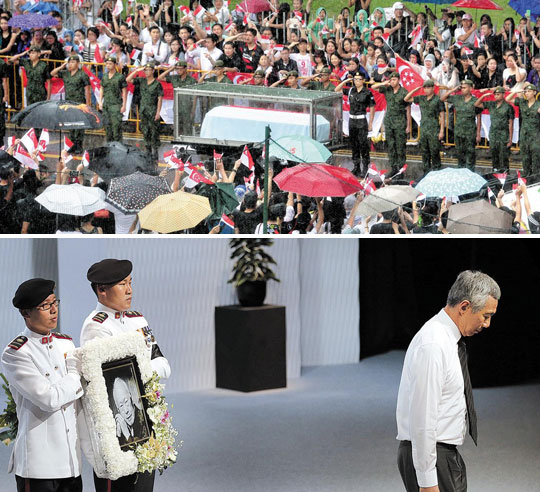 
		29일 리콴유 전 싱가포르 총리의 관을 실은 포차가 장례식장인 싱가포르대로 이동하는 동안 수많은 시민이 궂은 날씨에도 아랑곳하지 않고 운구 행렬을 지켜보며 국부(國父)에게 마지막 인사를 전했다(위 사진). 박근혜 대통령 등 세계 18개국 전·현직 정상이 참석한 장례식에서 고인의 아들 리셴룽 현 총리가 추도사를 마치고 퇴장하고 있다(아래 사진). /신화 뉴시스
