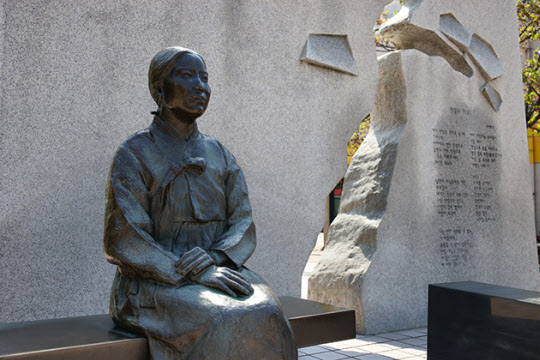 나혜석의 동상이 자신의 이름을 딴 거리에 자신의 시가 새겨진 비석 옆 좌석에 놓여있다.