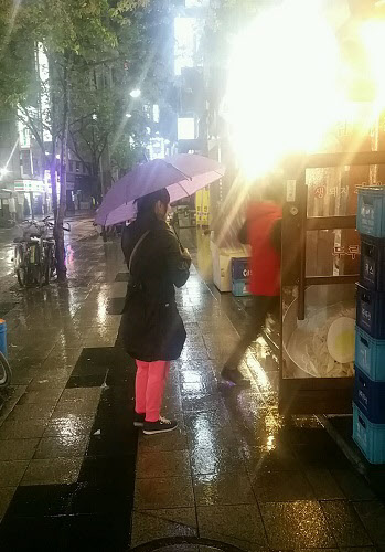 지난 15일 밤 11시쯤 서울 종로3가 거리에 빨간 바지를 입은 '올빼미 아줌마'가 빗속에 서 있다. /이벌찬 기자