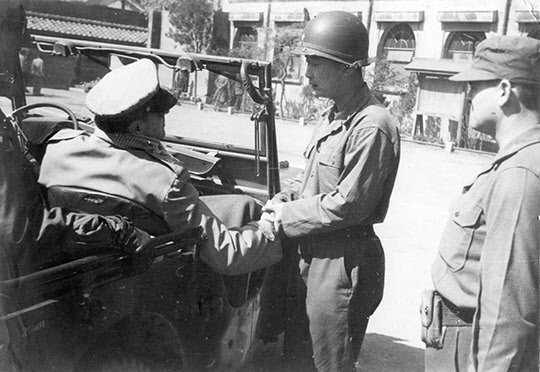 1951년 3월18일 만리동의 국군 1사단 지휘소를 찾은 맥아더(지프 앞 앉은 이) 유엔군 총사령관이 1사단장 백선엽 장군과 악수하고 있다.