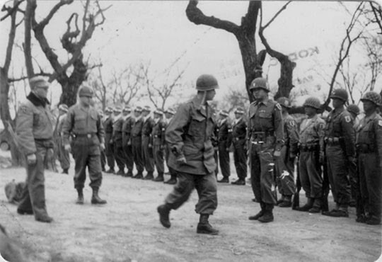 1951년 4월 7일 신임 국군 1군단장으로 발령을 받은 백선엽 당시 1사단장이 이임 전 사단 장병들을 사열하고 있다. 그 왼쪽 뒤가 프랭크 밀번 미 1군단장.