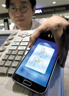 한 백화점에서 고객이 간편 결제 서비스 ‘삼성페이’가 설치된 스마트폰을 결제 단말기에 갖다대고 대금을 치르고 있다.