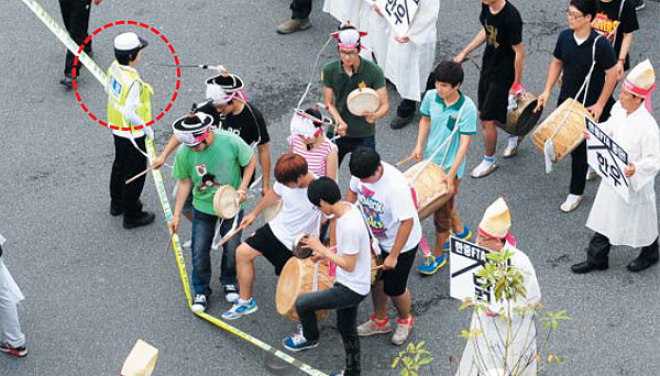 경찰은 허수아비? 우리나라 시위 현장에선 폴리스라인을 시위대가 조롱하듯 넘나드는 장면을 쉽게 찾아볼 수 있다. 2013년 부산 해운대에서 열린 ‘한·중 FTA 중단’ 집회에서 경찰(붉은색 원)이 지키고 있지만 풍물패가 아무런 제지도 받지 않고 폴리스라인을 넘고 있다. 