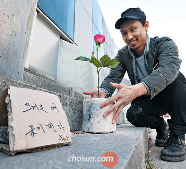 8일 오후 설치미술가 이효열씨가 서울시청 건너편 보행로 계단에 작품을 설치하며 환하게 웃고 있다. 이씨는 타고 남은 연탄을 꽃병 삼아 2013년부터 지금까지 ‘연탄꽃’ 작품 200여 점을 만들었다. 작품 옆에는 ‘뜨거울 때 꽃이 핀다’고 글을 썼다.