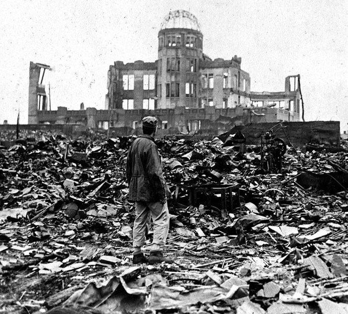 1945년 9월 7일 미군 군복을 입은 한 남성이 부서진 건물 잔해 위에 서서 뼈대만 남은 히로시마현 산업장려관 건물을 바라보고 있다.
