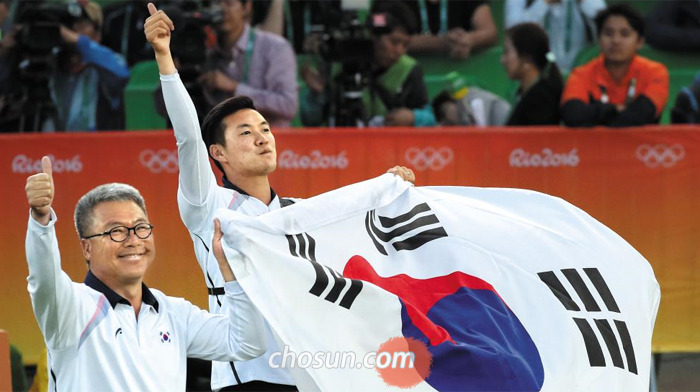 13일 남자 양궁 개인전에서 금메달을 딴 구본찬(오른쪽)이 박채순 남자팀 감독과 함께 엄지손가락을 하늘로 뻗은 채 태극기를 들고 우승 세리머니를 하고 있다.
