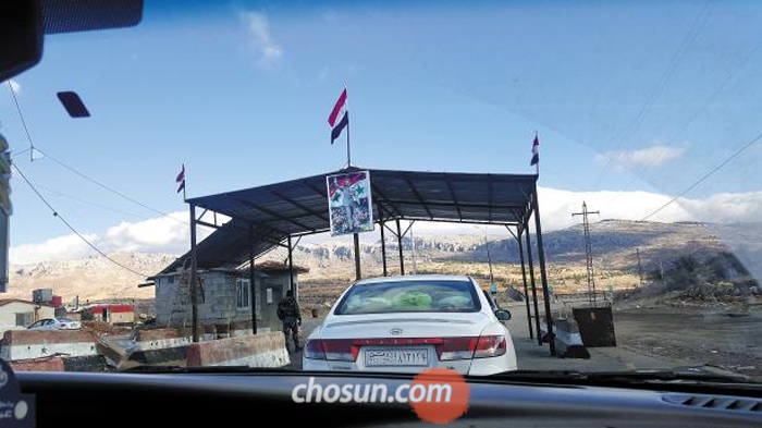 지난 13일(현지 시각) 시리아 번호판을 단 승용차가 레바논과 시리아 국경에 있는 출입국 검문소에서 검문을 받고 있다. 검문소에는 시리아 국기와 군복 차림을 한 아사드 대통령 사진이 걸려있다. 시리아 내전이 진정 국면으로 접어들면서 시리아로 들어가려는 차량이 급증했다.