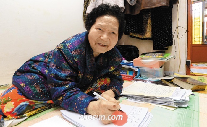 팔순 시인 김옥례씨가 월세방에서 이면지에 시를 쓰고 있다. 그는 “시 짓고 그림 그리는 곳이 꽃밭이요, 천국”이라고 했다.