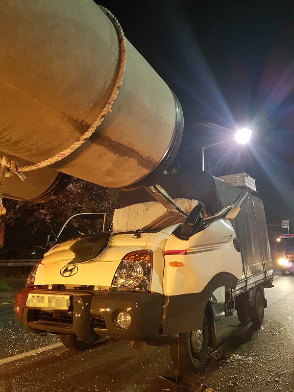 11일 오전 부산 강서구의 한 도로에서 1t 트럭이 트레일러에 실린 대형 콘크리트 기둥을 들이받는 바람에 운전석이 납작해졌다./연합뉴스