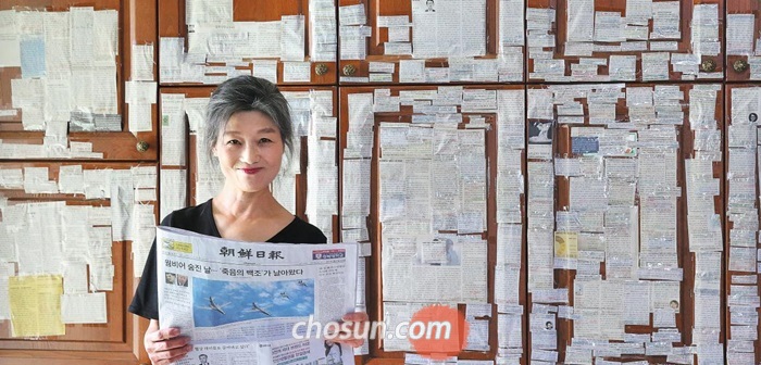 독자 임수련(57)씨가 지난 2년간 주방 벽에 붙여 놓은 조선일보 기사 스크랩 앞에서 활짝 웃고 있다.