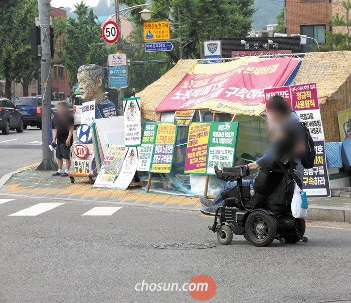 전동 휠체어를 탄 한 장애인이 20일 서울 종로구 청운효자동주민센터에서 횡단보도가 아닌 차도로 길을 건너고 있다.