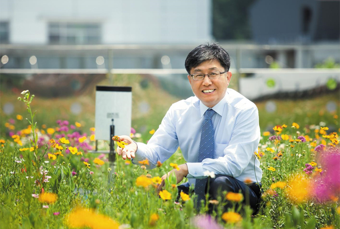 한무영 서울대 건설환경공학부 교수가 지난 5월 ‘빗물 정원’에 핀 꽃 옆에 앉아 활짝 웃고 있다. 한 교수는 가뭄과 폭염 등을 해결하기 위해 서울대 건물 옥상에 빗물을 저장할 수 있는 정원을 만들었다.