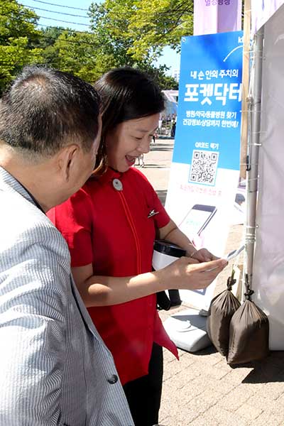 지난 16일 진행된 실버문화페스티발에서 포켓닥터 직원과 KT그룹 IT서포터즈들이 어르신에게 스마트폰으로 병원 찾는 방법 등을 설명하고 있다.