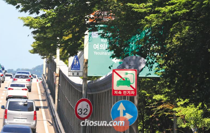 서울 영등포구 여의도동 여의대방로 샛강역에서 원효대교 방향에 있는 한 도로 안내 표지판이 가로수에 가려 보이지 않는다. 좌회전하면 마포대교·여의나루역·여의도한강공원, 우회전하면 63빌딩 방향임을 알리는 표지판이지만 운전 중에는 보기 어렵다. 사진은 원효대교 남단 고가에서 찍은 것이지만 표지판은 바로 옆 여의대방로에서도 보이지 않는다.