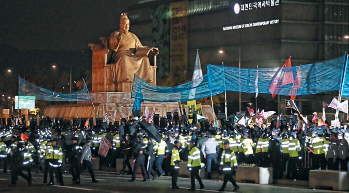 7일 밤 서울 광화문광장에 있던 반미 시위대가 트럼프 대통령 차량이 지나갈 것으로 예상한 세종문화회관 앞 도로 쪽으로 쓰레기를 던지자 경찰이 그물망을 펼쳐 이를 막고 있다.