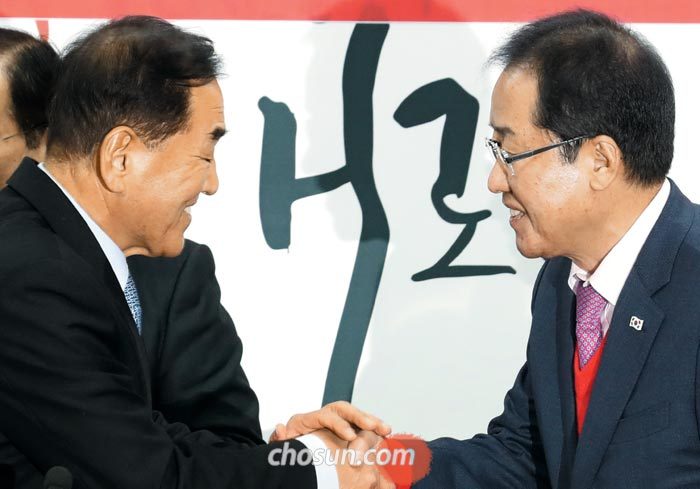 자유한국당 홍준표(오른쪽) 대표가 12일 오전 서울 여의도 당사에서 열린 입당 행사에서 이재오 전 의원과 악수를 하고 있다.