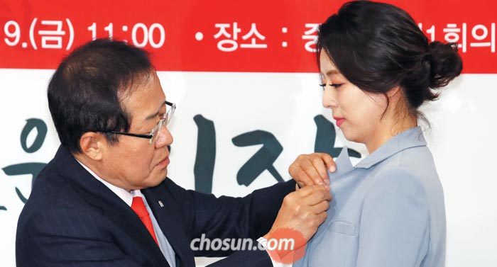 자유한국당 홍준표 대표가 9일 서울 여의도 당사에서 입당식을 가진 배현진 전 MBC 아나운서에게 태극기 배지를 달아주고 있다