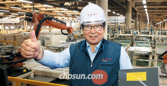 지난 12일 경기 안산 시화공단에 있는 한샘 3공장에서 최양하 회장이 도어 샘플을 들고 엄지손가락을 치켜세우고 있다. 최 회장 뒤로 자동화 생산 라인에서 로봇들이 부엌 가구 자재를 포장하고 있다.
