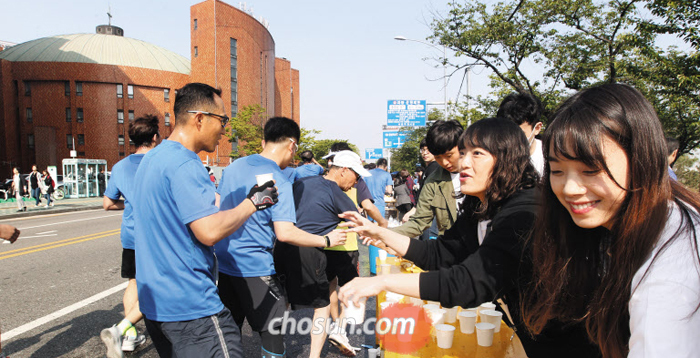 29일 ‘2018 서울하프마라톤’이 열린 서울 여의도순복음교회 앞에서 이 교회 자원봉사자들이 물과 음료를 나눠주고 있다.