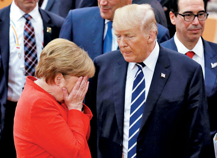 지난해 7월 독일 함부르크에서 열린 G20 정상회의 행사장에서 메르켈(왼쪽) 독일 총리가 트럼프 미국 대통령 앞에서 손으로 얼굴을 감싼 채 고개를 숙이고 있다.