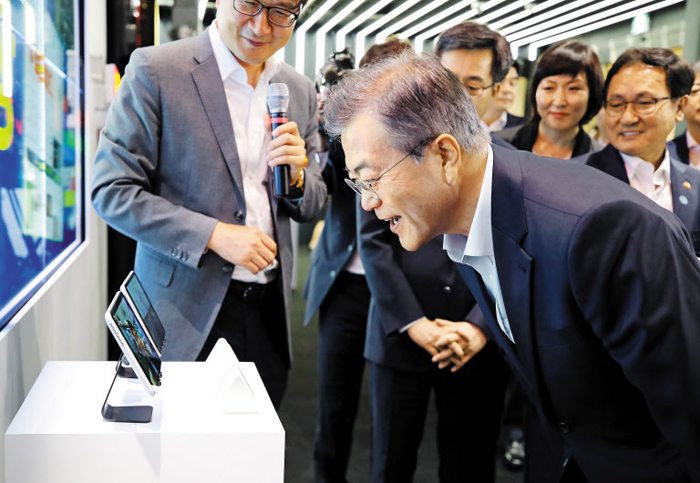 5G 기술 체험하는 문재인 대통령 - 문재인 대통령이 17일 서울 강서구 마곡 R&D 단지에서 열린 혁신 성장 보고대회에서 5G를 이용한 태블릿PC를 통해 화면 속 SK텔레콤 관계자와 대화하고 있다. 문 대통령은 이날 행사에서 미세 먼지를 저감하는 수소전기차 버스, 드론의 다양한 기능을 직접 체험하고 “혁신 성장의 걸림돌인 규제를 혁신하는 데 더 속도를 내야 한다”고 말했다.