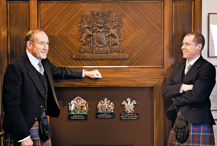 킬트를 입은 더글러스 킨록앤더슨(왼쪽) 킨록앤더슨 회장이 최고경영자(CEO)인 아들 존과 영국 왕실 인증 문양이 장식된 벽난로 앞에 서 있다.