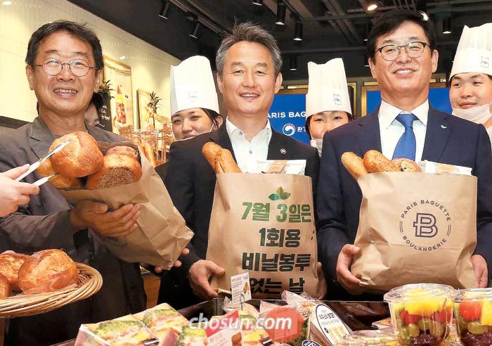 2일 일회용품 줄이기 협약을 맺은 안병옥(가운데) 환경부 차관과 권인태(오른쪽) 파리크라상 대표이사가 비닐 쇼핑백 대용으로 쓸 종이 봉투를 들어 보이고 있다.