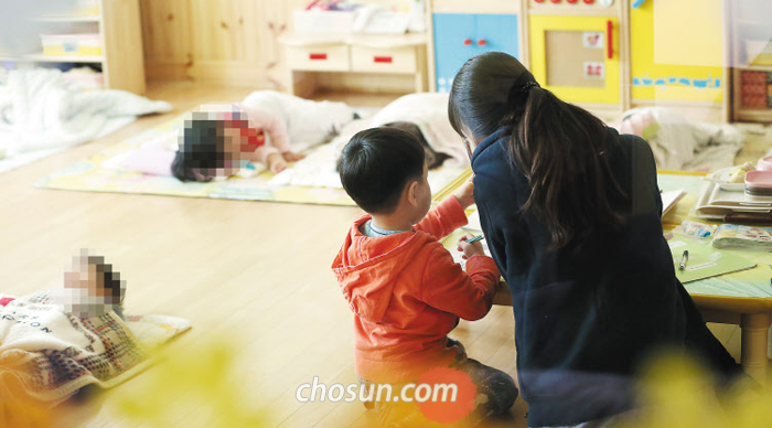 서울 성동구의 한 어린이집에서 보육교사가 낮잠 시간에 깨어 있는 아이를 돌보고 있다. 보육교사에게 의무 휴식 시간을 보장하는 법이 7월부터 시행되자 정부는 낮잠 시간을 교사 휴식시간으로 활용하라는 지침을 내렸다.