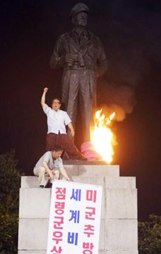 27일 새벽 좌파 단체‘평화협정운동본부’소속 회원 이모(61) 목사와 안모(60) 목사가 인천 중구 자유공원에 있는 맥아더 장군 동상에 불을 지르고 구호를 외치고 있다.