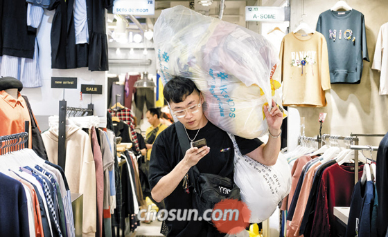 지난 5일 자정 서울 동대문시장의 한 도매 상가에서 스타트업 링크샵스 직원이 옷이 가득 담긴 비닐봉지를 어깨에 짊어진 채 나오고 있다.