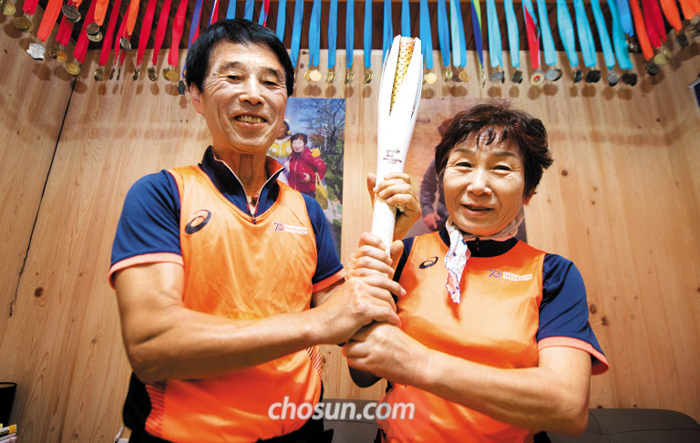 소문난 마라톤 마니아 서광수(왼쪽)·신영옥씨 부부는 둘 합쳐 1200여 회 완주 경험 중에서 최고로 ‘춘천마라톤’을 꼽았다. 11일 춘천마라톤 기념 유니폼을 입고 평창올림픽 성화봉을 든 부부. 서씨가 작년 11월 부산 지역 성화 봉송 때 들고 달린 후 기념으로 산 것이다.