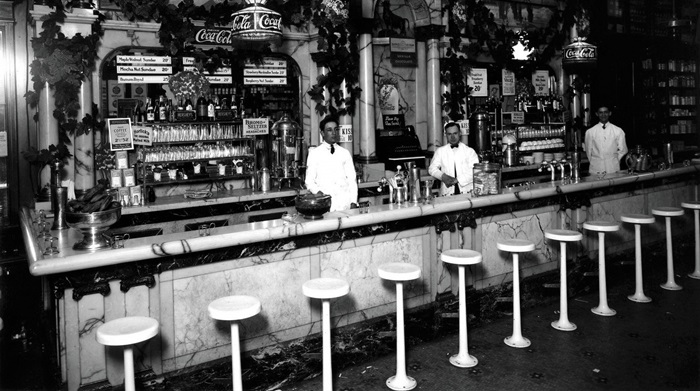 1915년 미국 노스캐롤라이나 더럼시 중심가의 ‘소다 분수(soda fountain)’ 가게. 천장에는 코카콜라 로고로 장식된 조명이 반짝이고 있다.