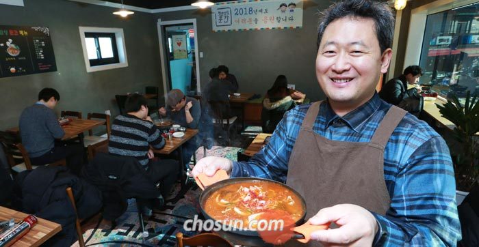 10일 오후 서울 성북구 정릉시장에서 '청년식당 문간'을 운영하는 이문수 신부가 김치찌개가 든 냄비를 들고 환하게 웃고 있다.