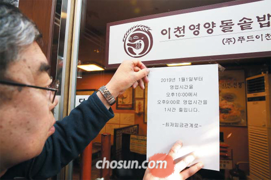 한 시간 일찍 문 닫습니다 - 지난 8일 서울 종로구 평창동에 있는 한식집 이천영양돌솥밥 사장 황태근씨가 식당 앞 유리창에 영업시간 단축을 공지하는 안내문을 붙이고 있다. 올해 또 한 번의 최저임금 인상으로 인건비 부담이 커지자 황씨는 영업 마감 시각을 기존 오후 10시에서 한 시간 앞당겼다.