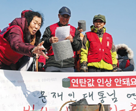 지난 23일 오전 서울 종로구 청와대 앞 분수대 광장에서 기자회견 참가자들이 연탄값 인상에 항의하며 연탄 모형을 던지고 있다. 