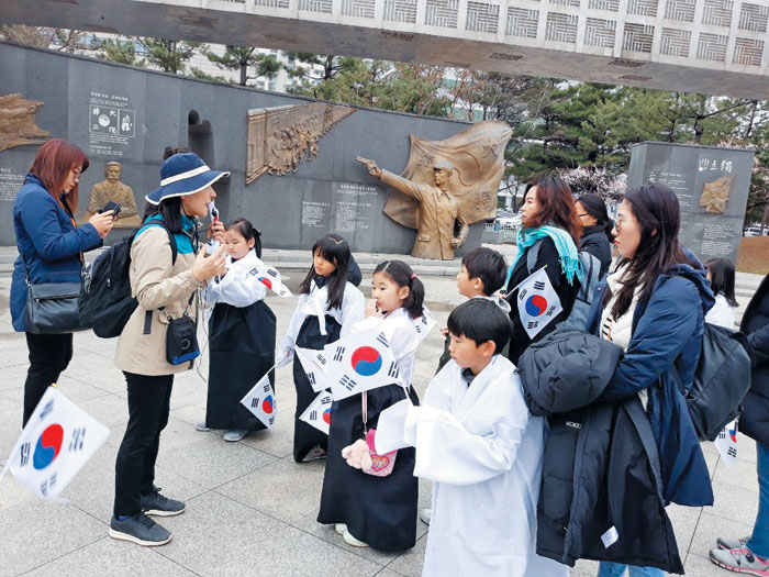 안중근공원에서 태극기를 들고 해설사의 설명을 듣고 있는 부천시티투어 참가자들.